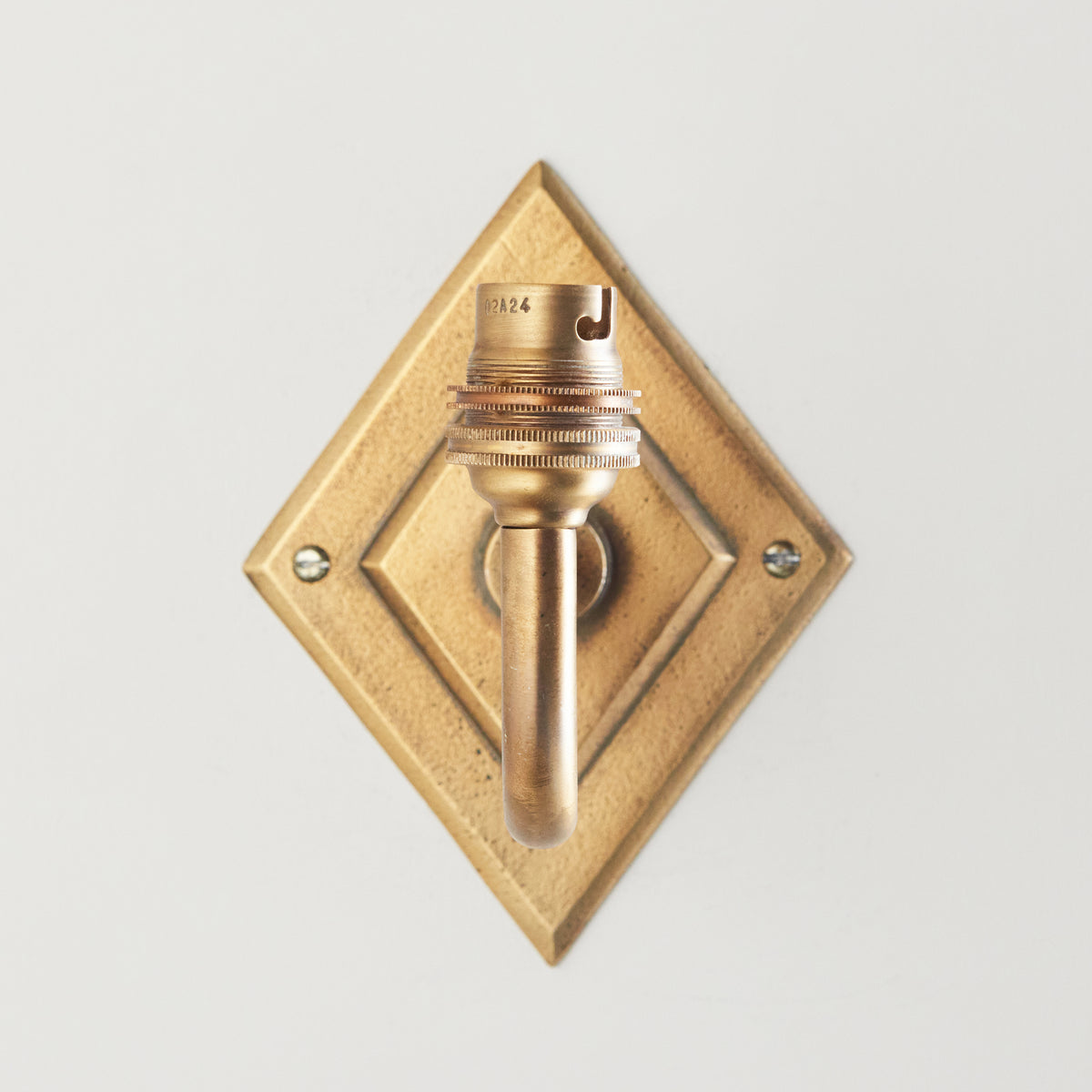 Head-on view of the Diamond Curve wall light showing the recessed diamond brass plate and lampholder
