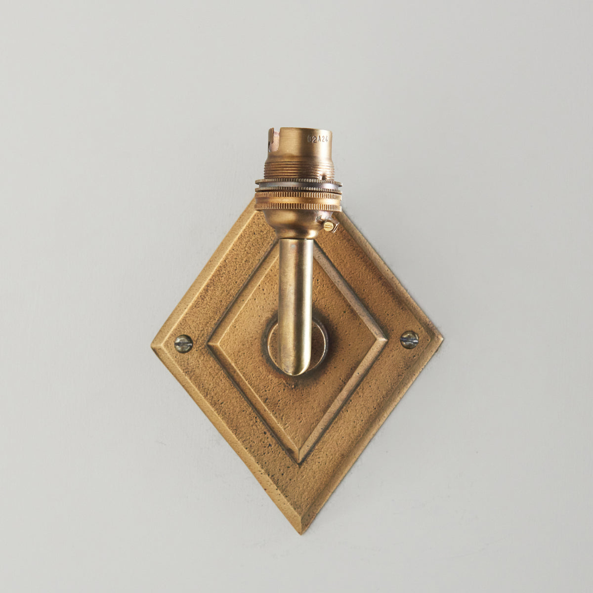 Head-on view of the Diamond Angle wall light with recessed diamond brass backplate and upright lampholder