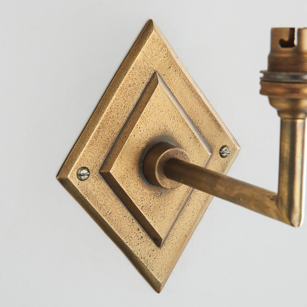 Close crop of the diamond backplate and arm collar on the Diamond Angle antique brass wall light