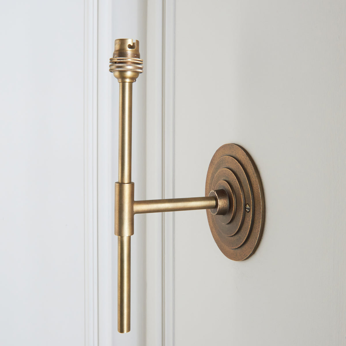 Angled view of the Halo Tall wall light, showing the stepped brass halo backplate and tall brass stem