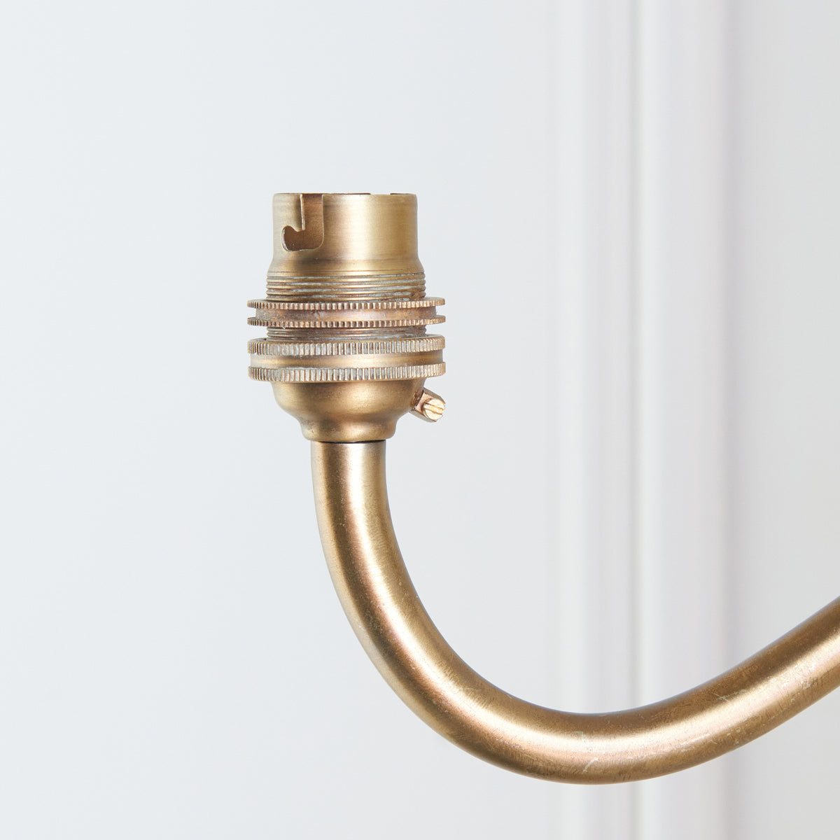 Tight crop of the brass bayonet lampholder at the tip of the Dahlia Curve wall light's arm