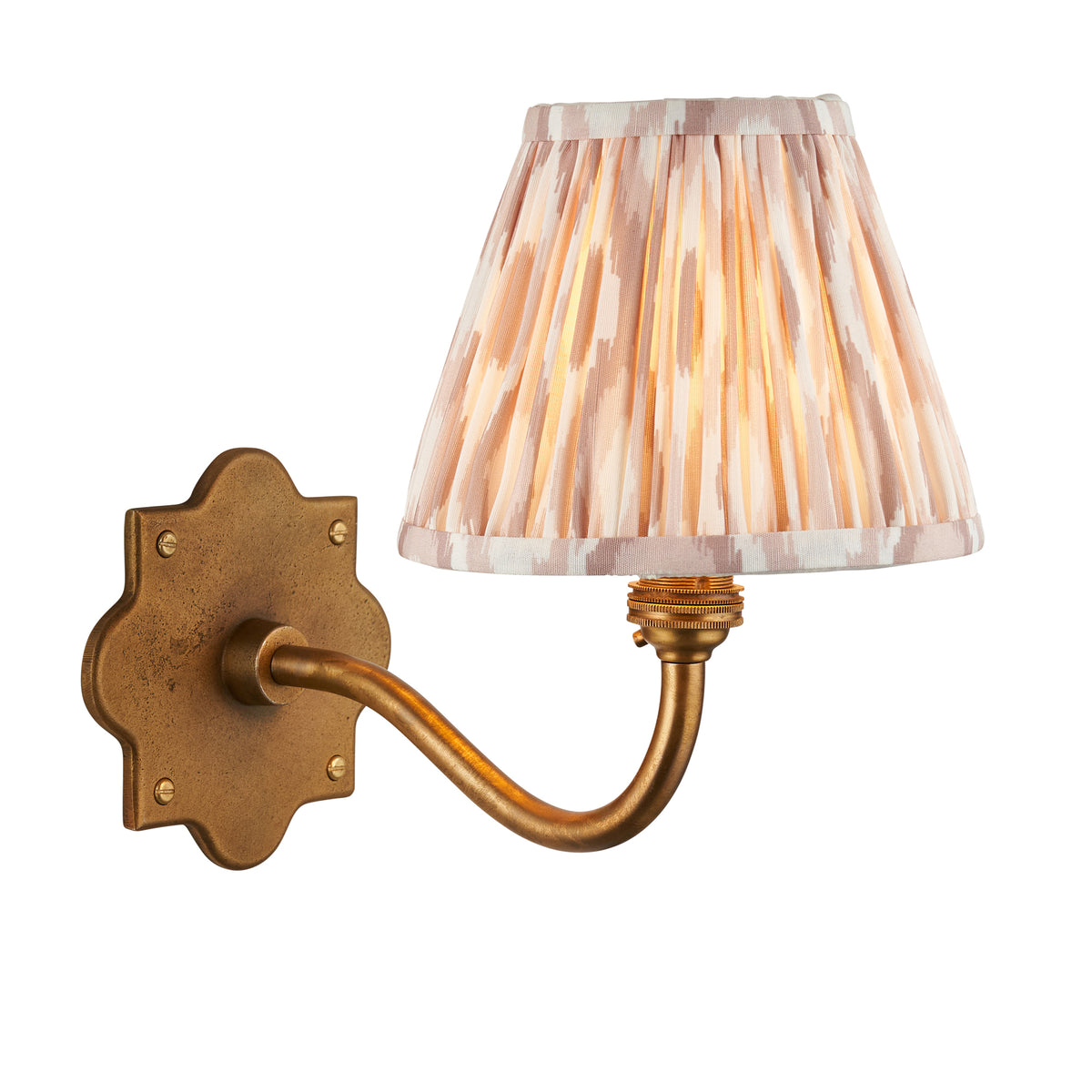 Anvil Curve antique brass wall light with pleated natural ikat tapered shade on a white background