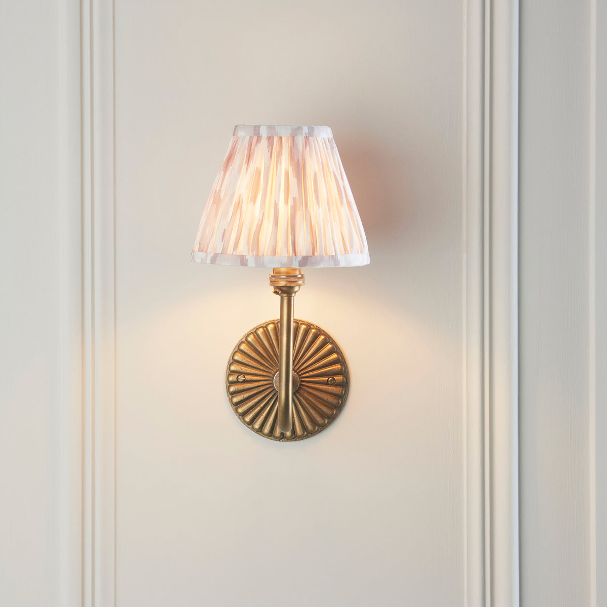 Front view of the Dahlia Swan wall light, fluted brass backplate and natural ikat pleated shade