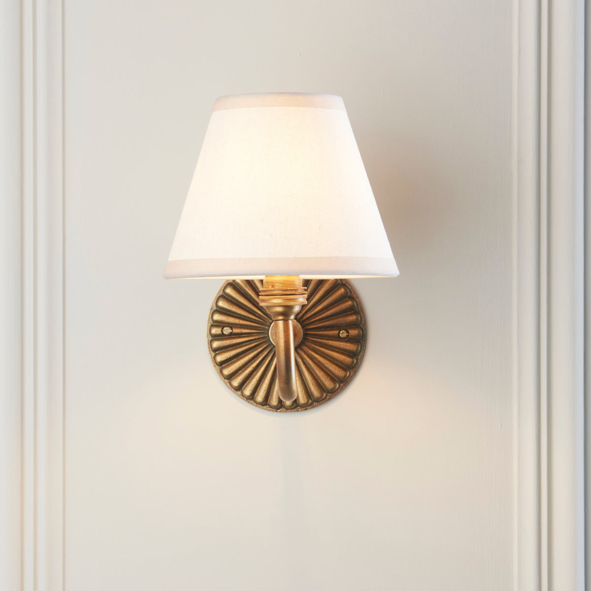 Front view of the Dahlia Curve & Ivy sconce, ribbed brass backplate under a plain white shade