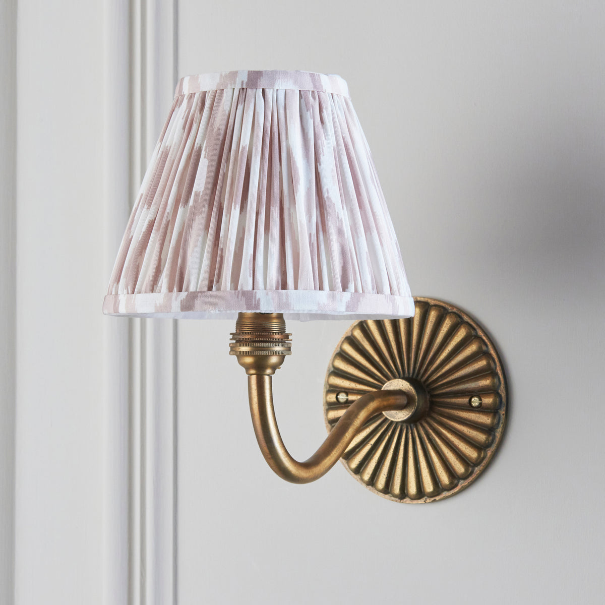 Side view of the Dahlia Curve wall light showing its neutral ikat shade and brass swan-neck arm
