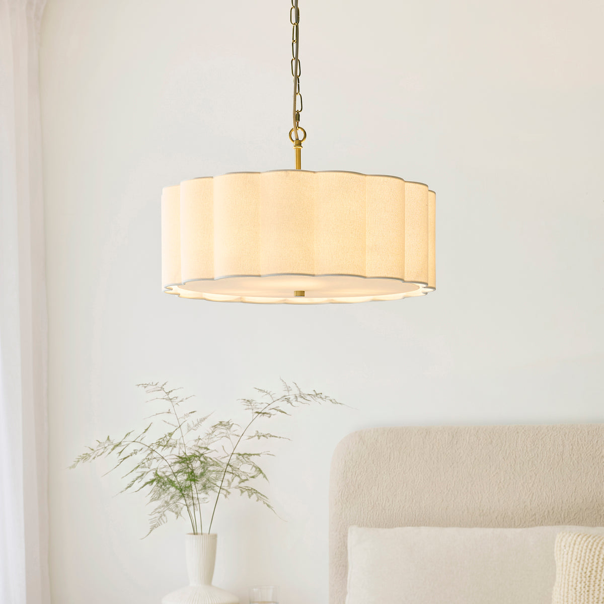 Lit Serene fluted cream pendant hanging in a bedroom beside a boucle headboard and oak bedside table