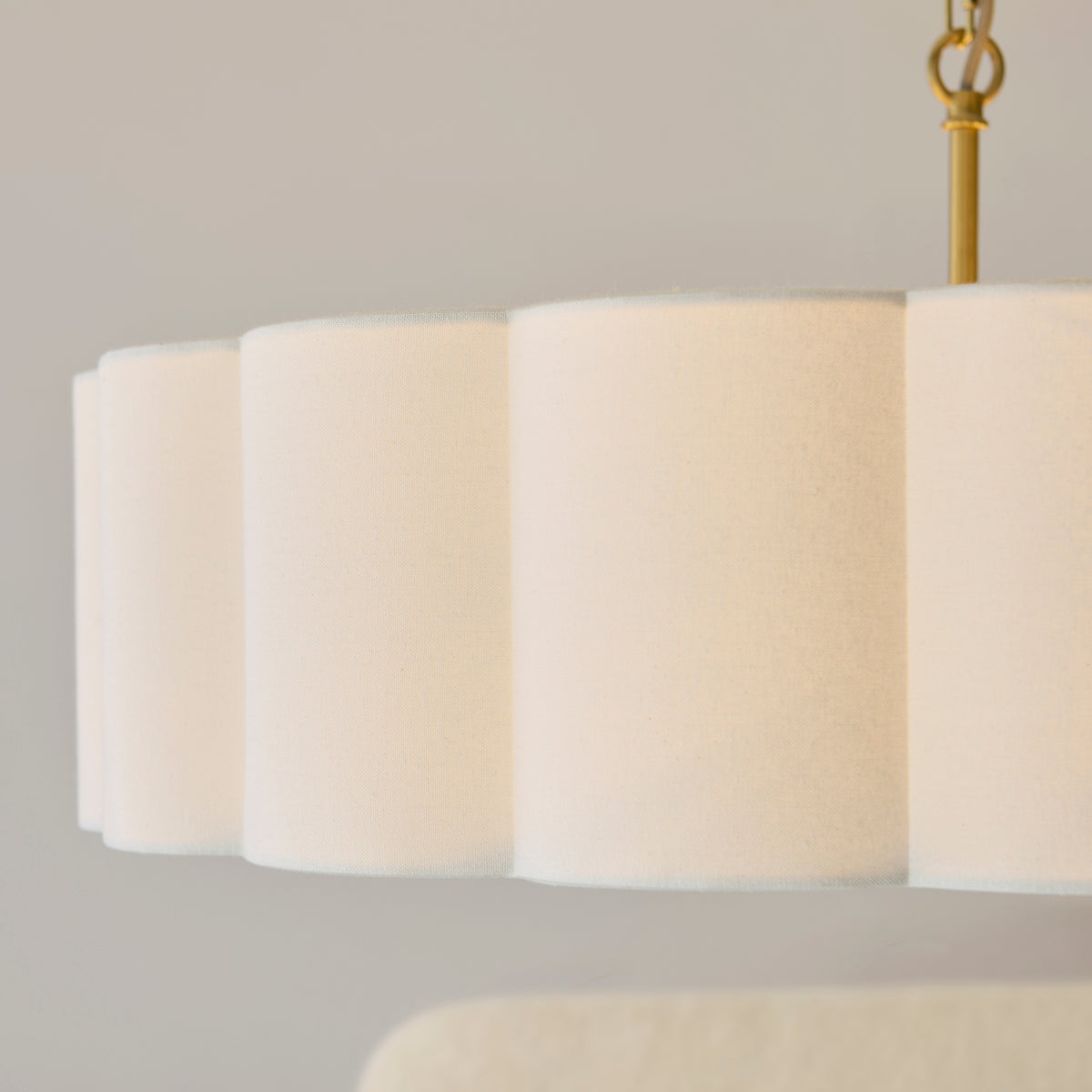 Close-up of the scalloped cream fabric shade and brass suspension loop of the Serene chandelier