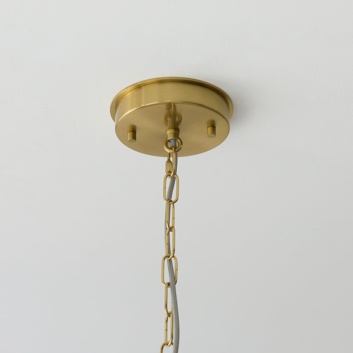 Close-up of the brushed aged brass ceiling plate and chain suspension