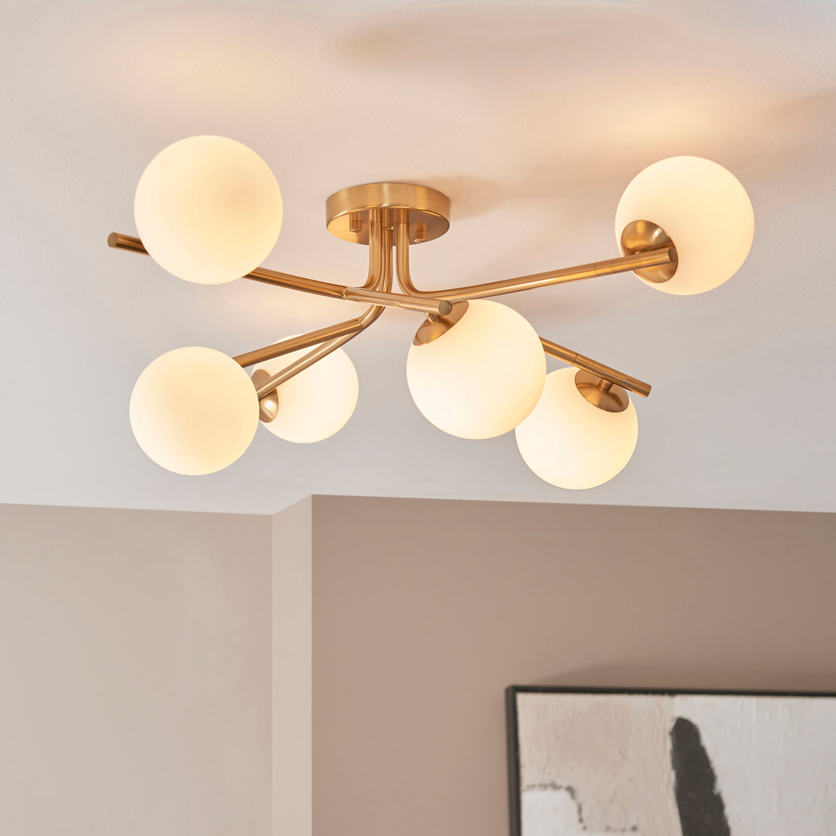 Six opal globes of the Aaron aged brass semi flush light seen from below in a white corner
