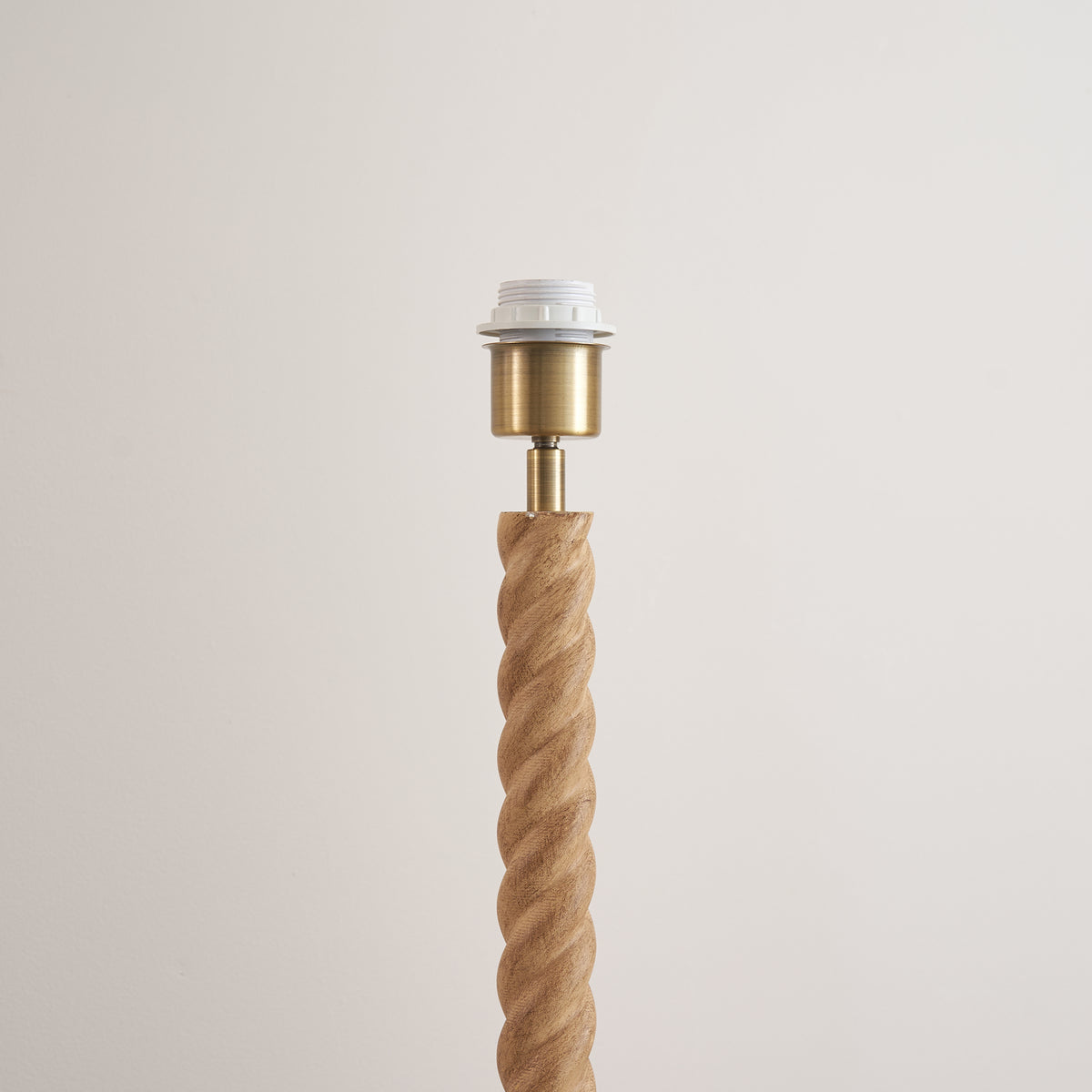 Brass lampholder and white shade ring atop the twisted oak effect floor lamp stem