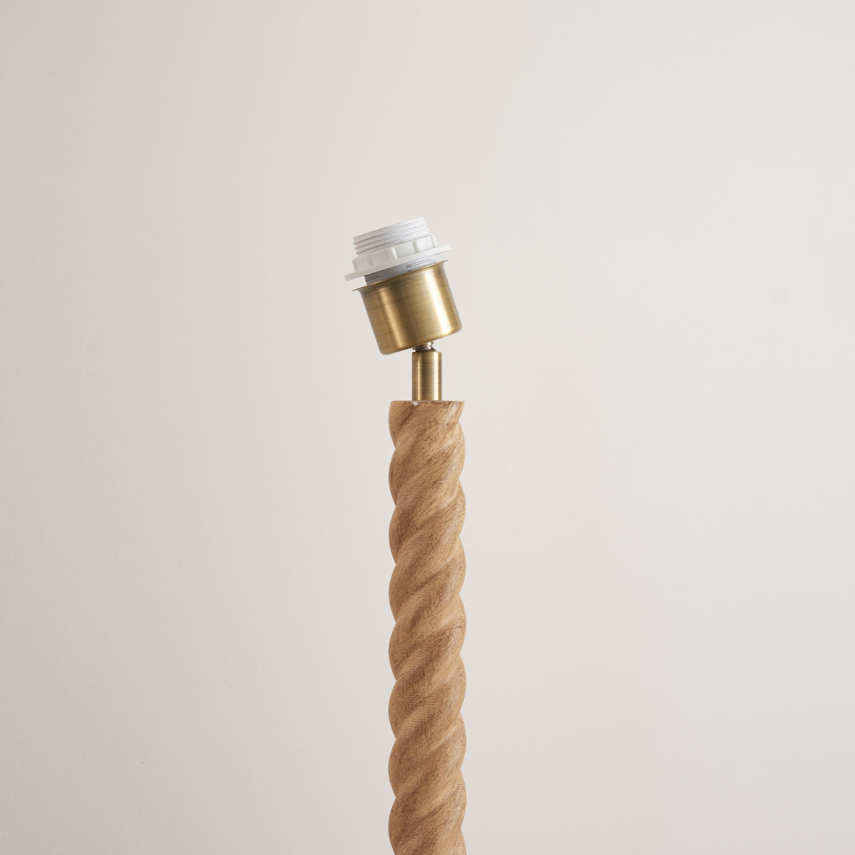 Angled close-up of the antique brass lampholder on the Twist oak effect floor lamp base