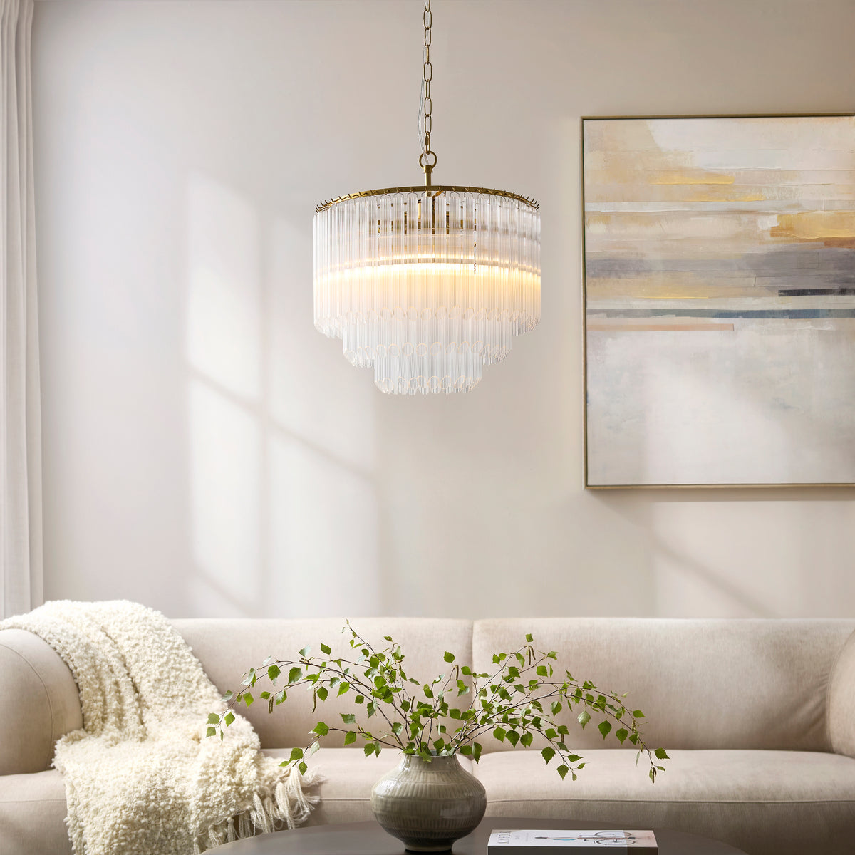 Montpellier ribbed glass chandelier lit above a cream sofa with a framed abstract artwork