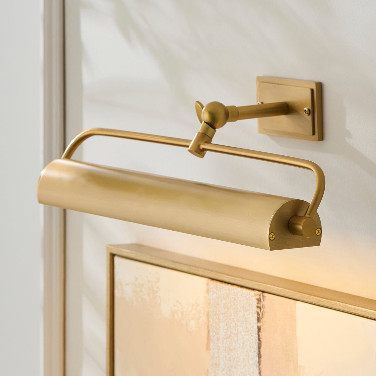 Nantes picture light in warm brass mounted above a framed picture on a white wall