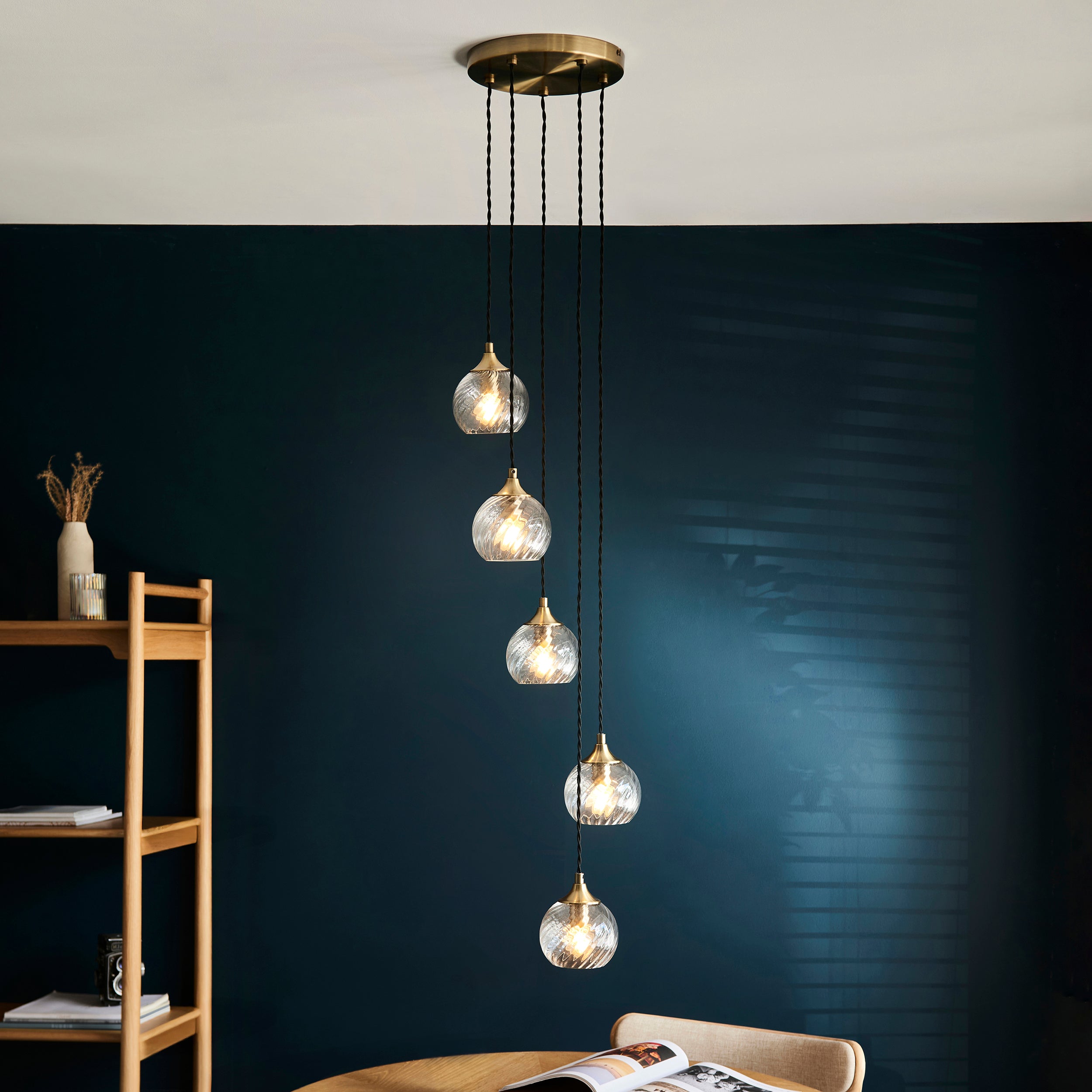 Modern pendant light with glass bulbs hanging against a dark wall.