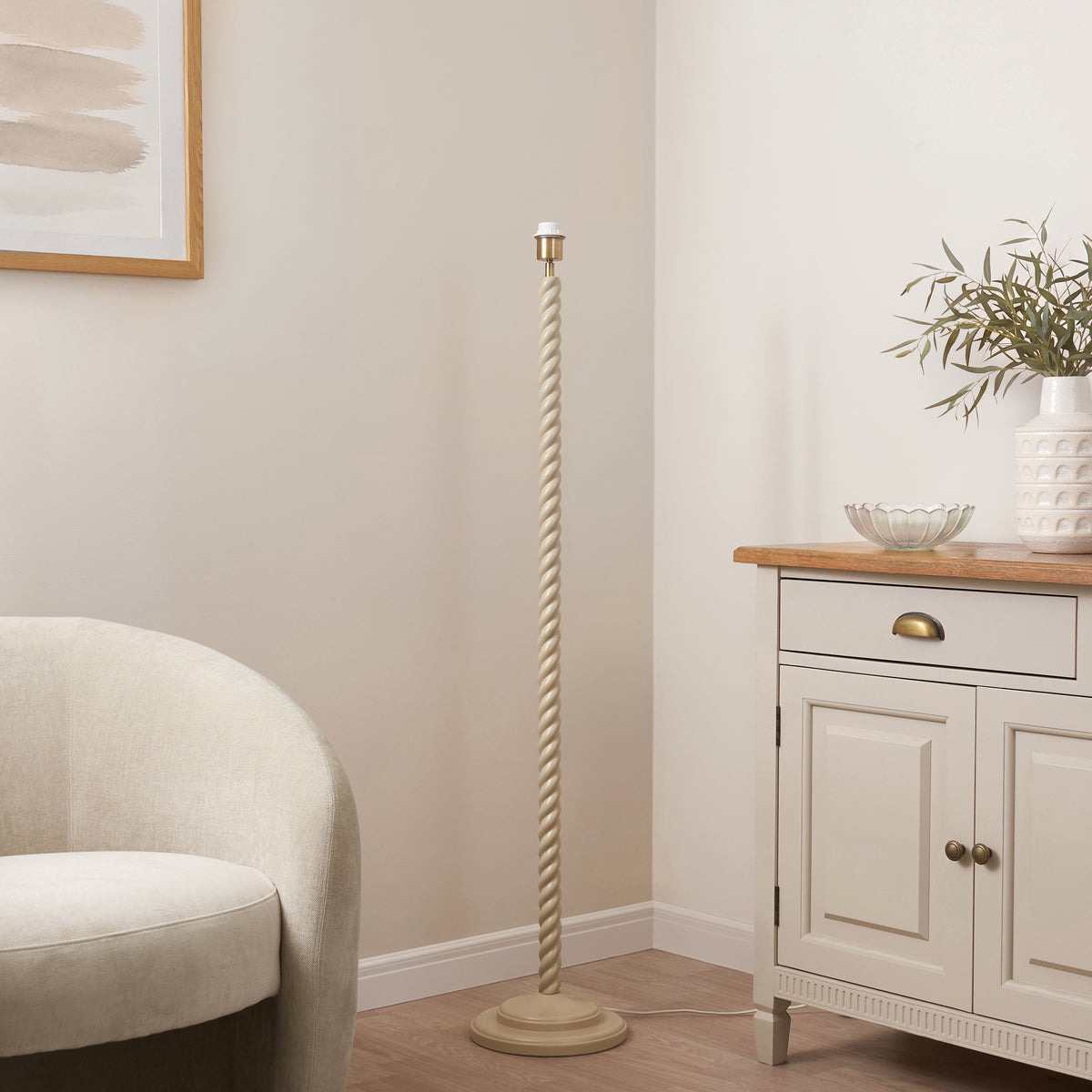 Twist almond white floor lamp base beside a cream armchair and oak sideboard in a living room