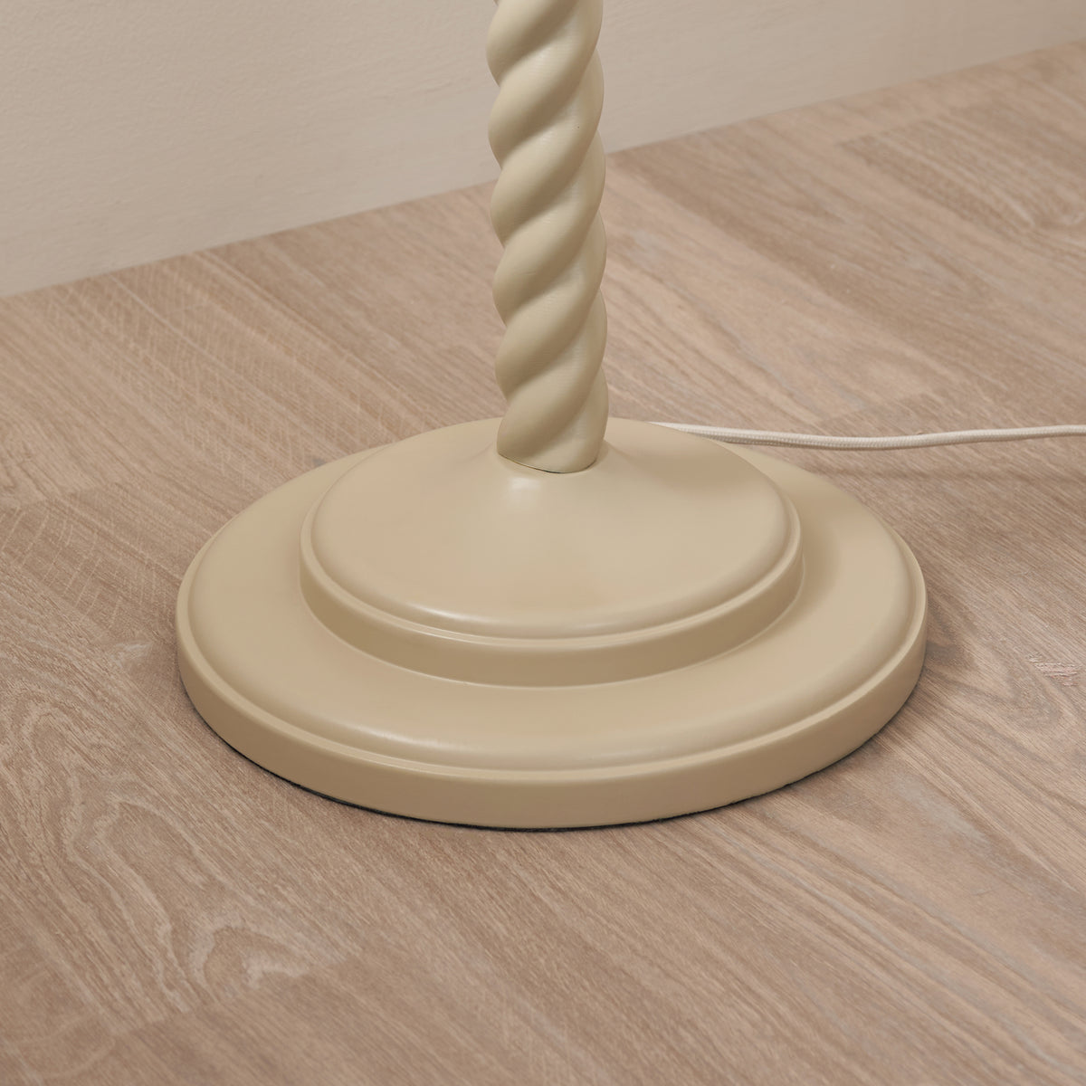 Close-up of the Twist floor lamp's stepped almond white base on a wooden floor