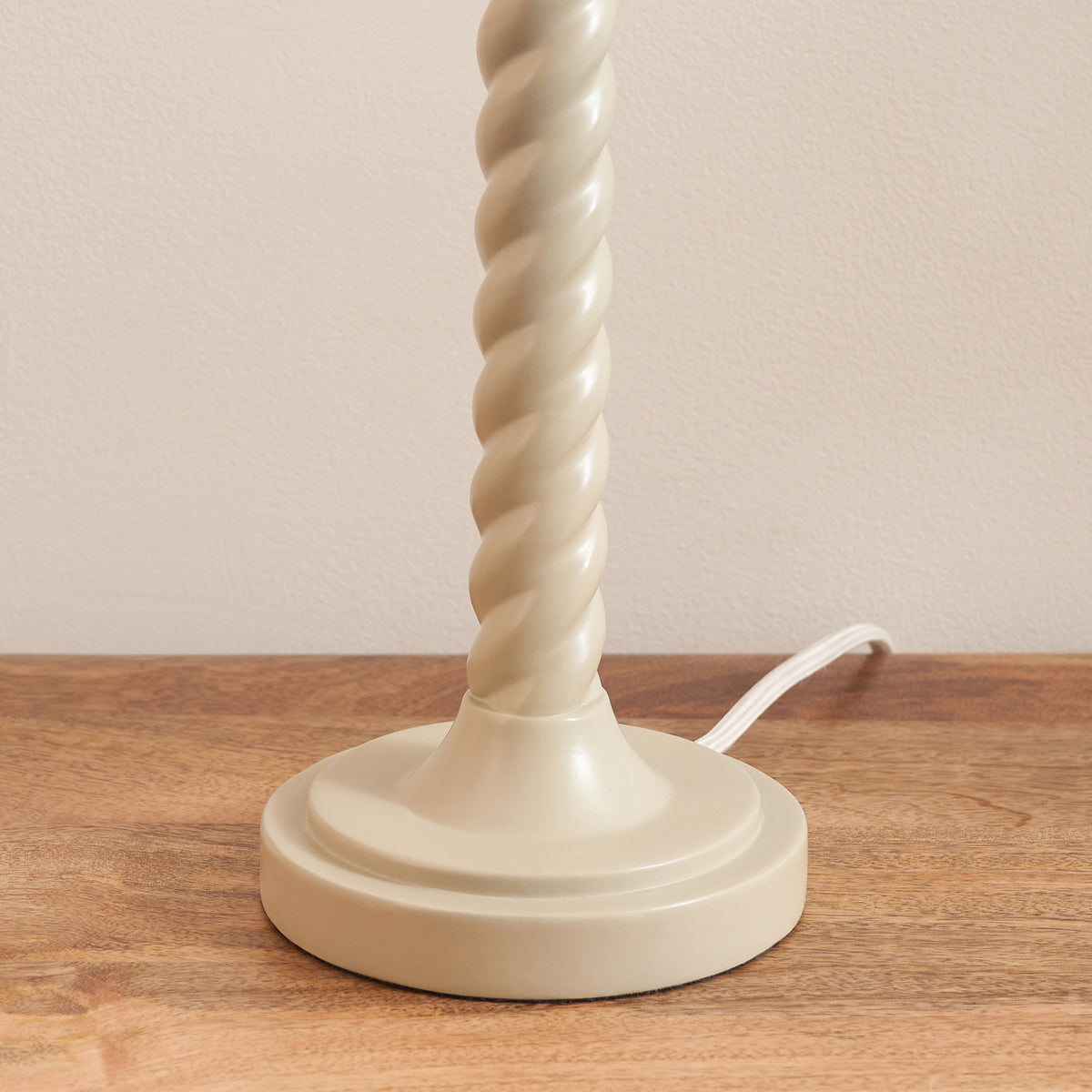 Close-up of the Twist table lamp's round stepped almond white base on oak wood