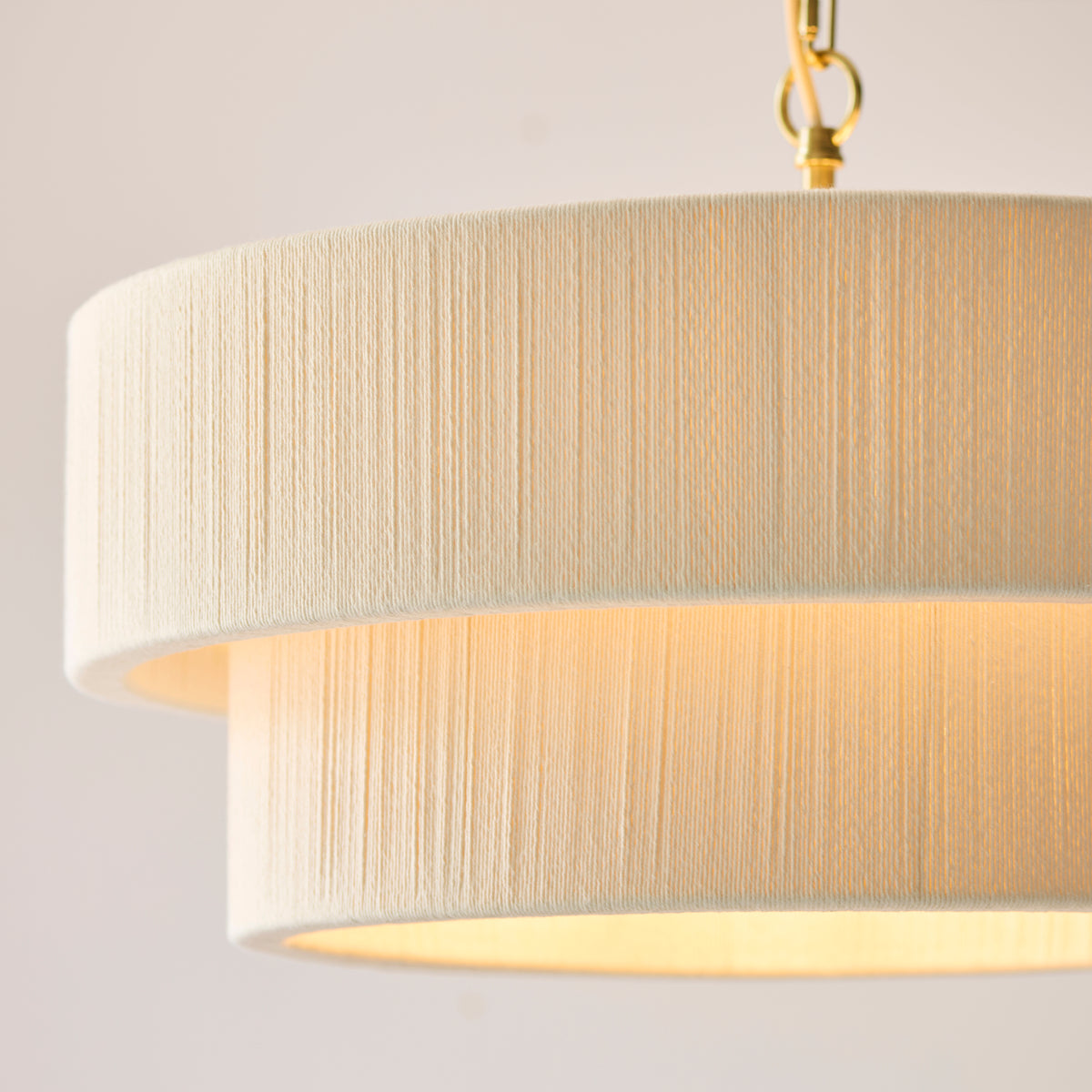 Close-up of the Noah pendant's stacked cream thread-wrapped shades and brass chain