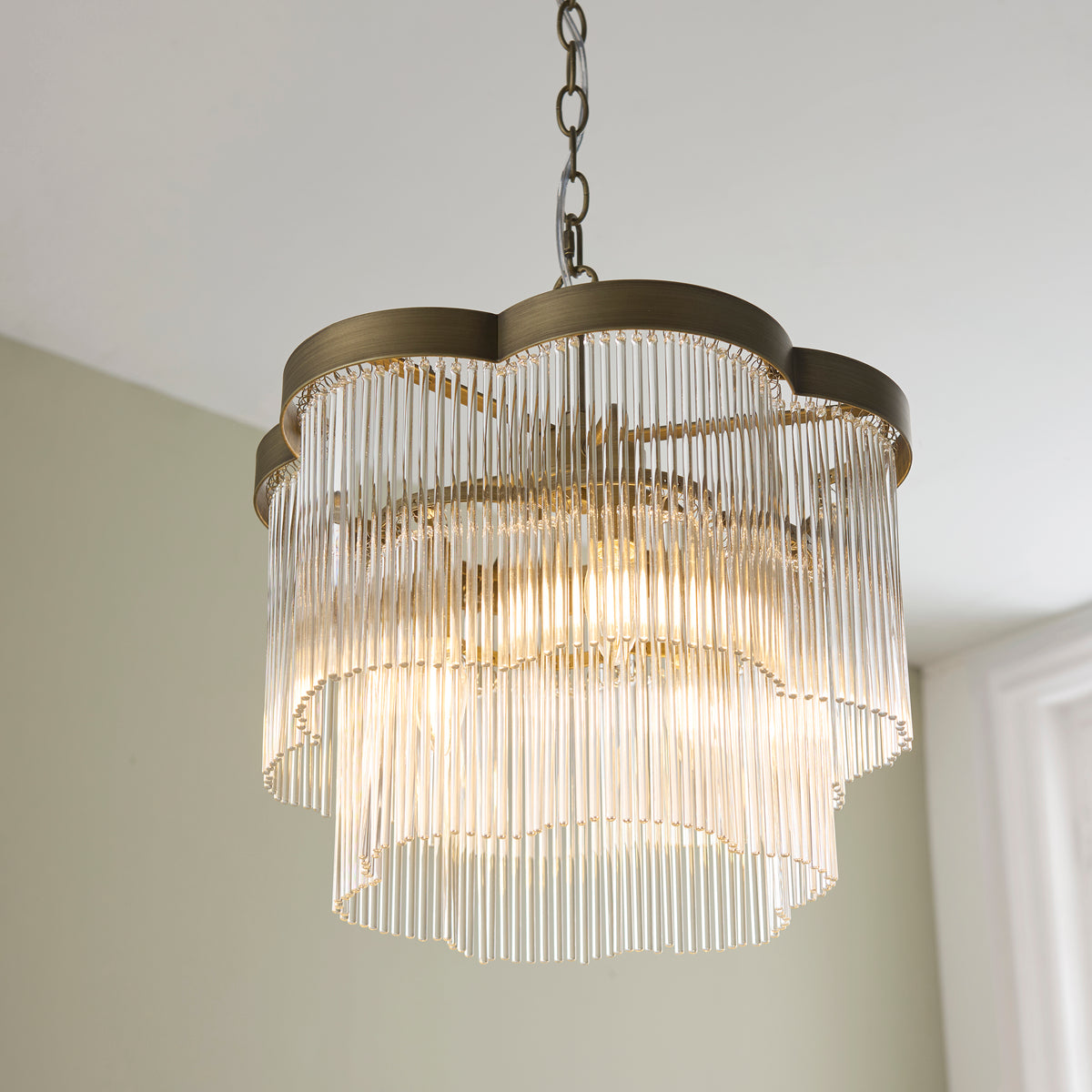 Lucille chandelier viewed from beneath, showing scalloped brass frame and glass rod tiers