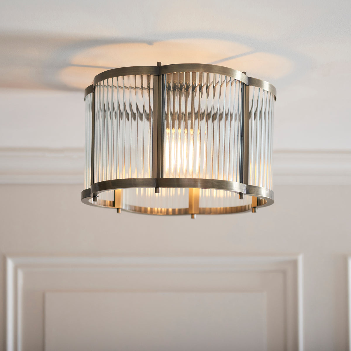 Ridgeton Scallop flush ceiling light glowing beneath white coving, seen at an angle