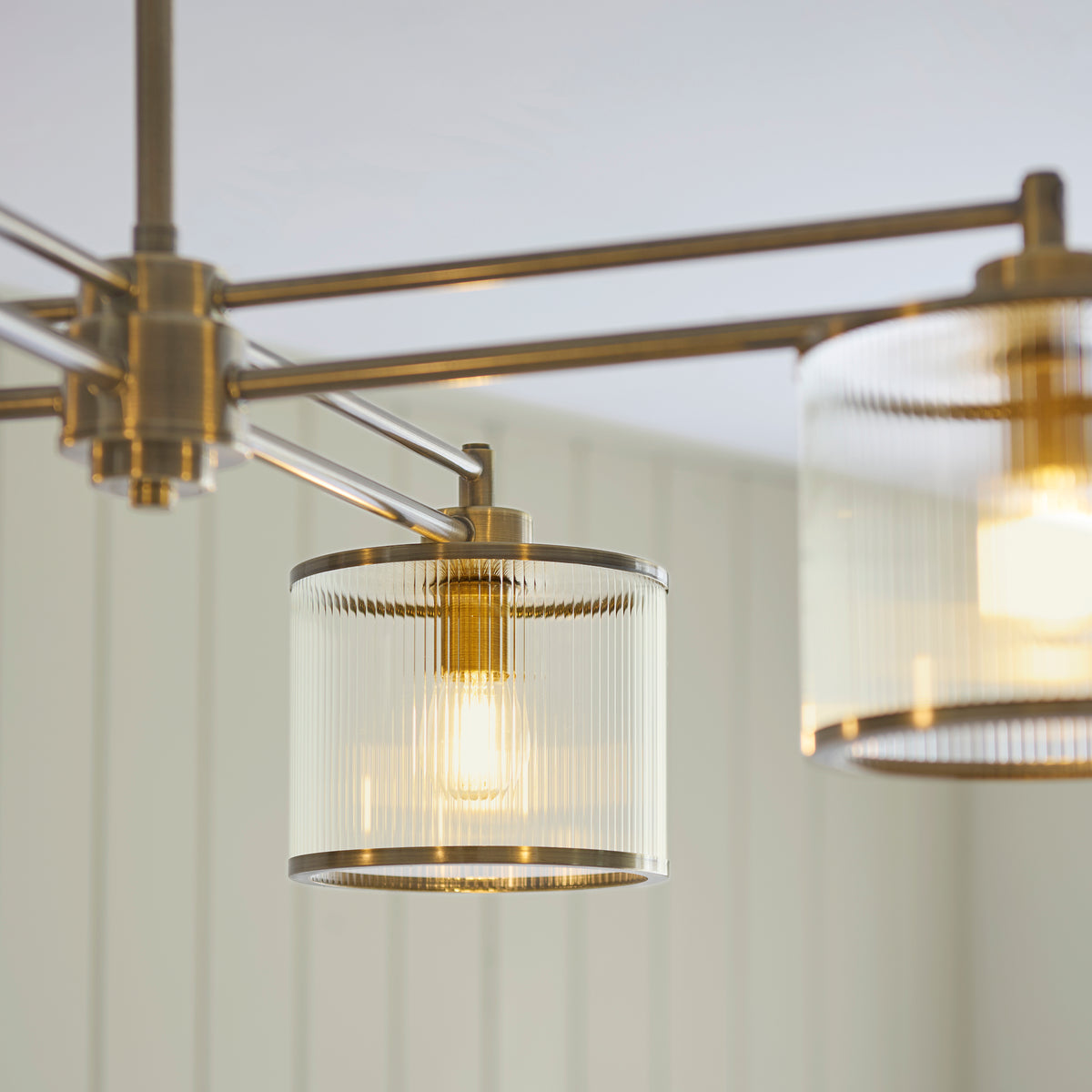 Close-up of two Ridgeton ribbed glass drum shades with brass rims and exposed filament bulbs