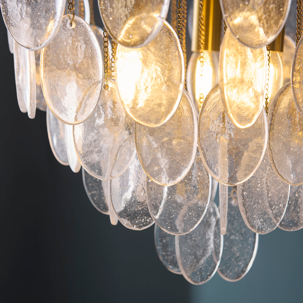 Detail of overlapping oval bubble glass plates on the Loretta pendant catching warm light