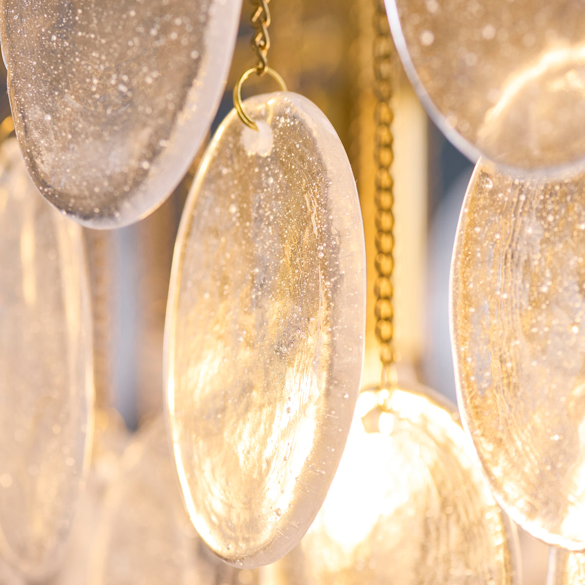 Close-up of textured bubble glass discs on fine brass chains within the Loretta pendant