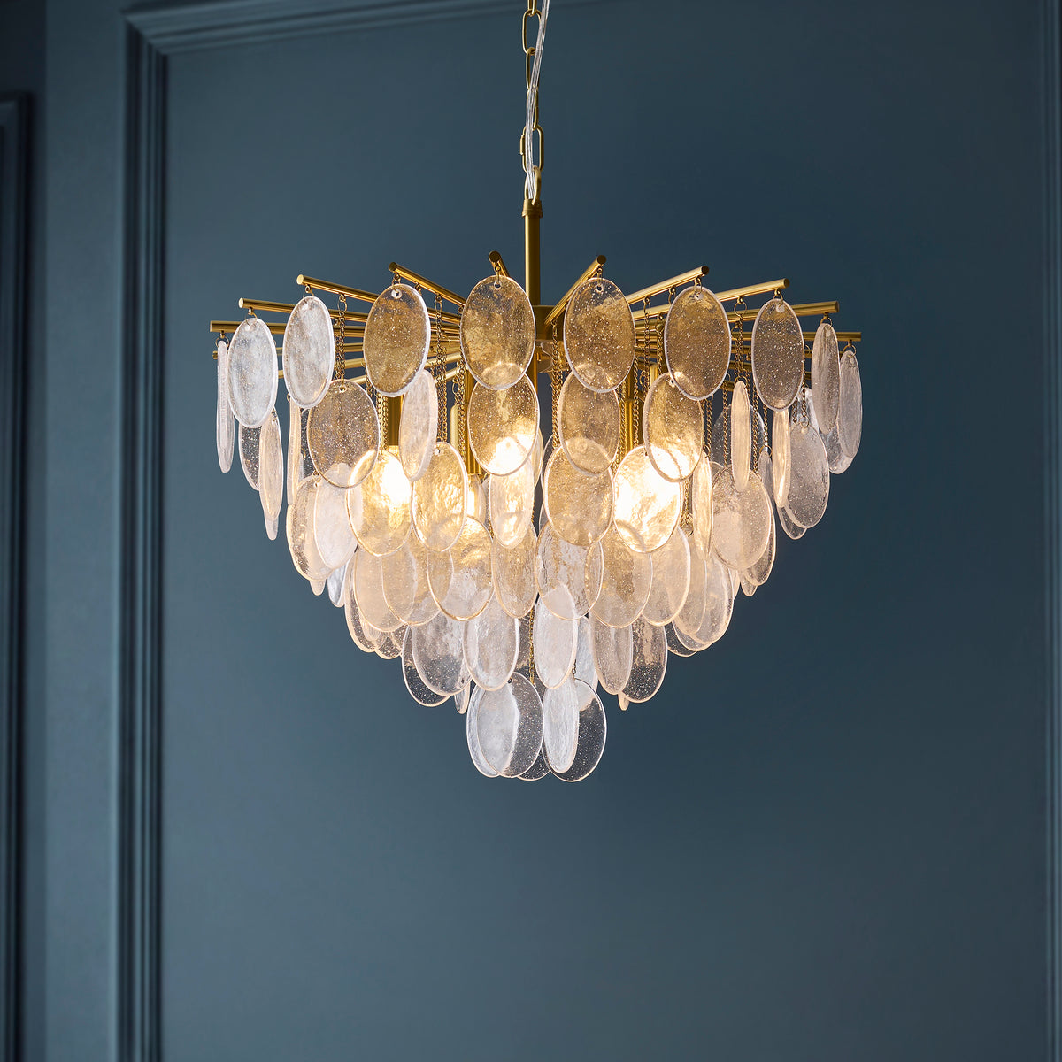 Loretta chandelier glowing against dark blue panelling, showing its layered bubble glass discs