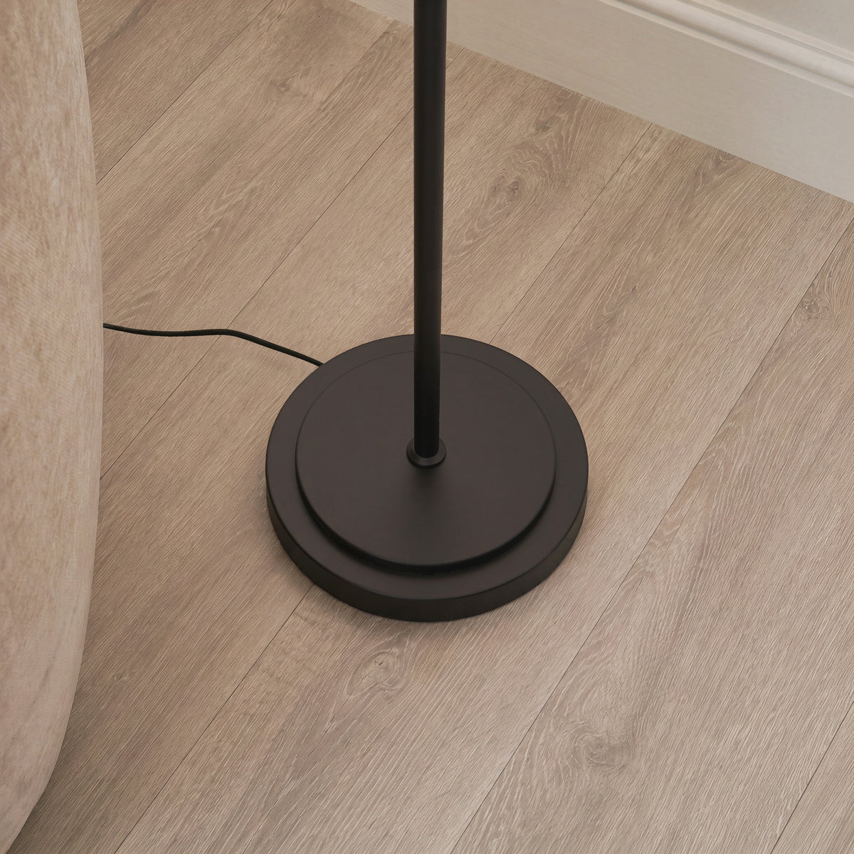 Close view of the Arlo floor lamp's matt black stepped base on pale wood flooring