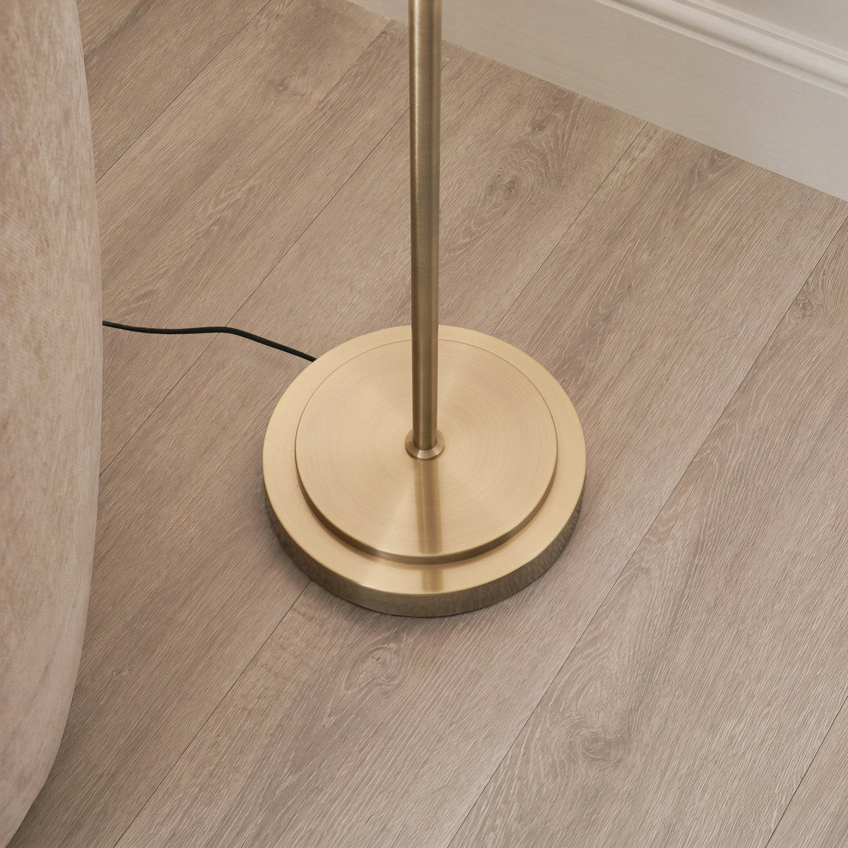 Close-up of the Arlo antique brass stepped floor lamp base on light wood flooring