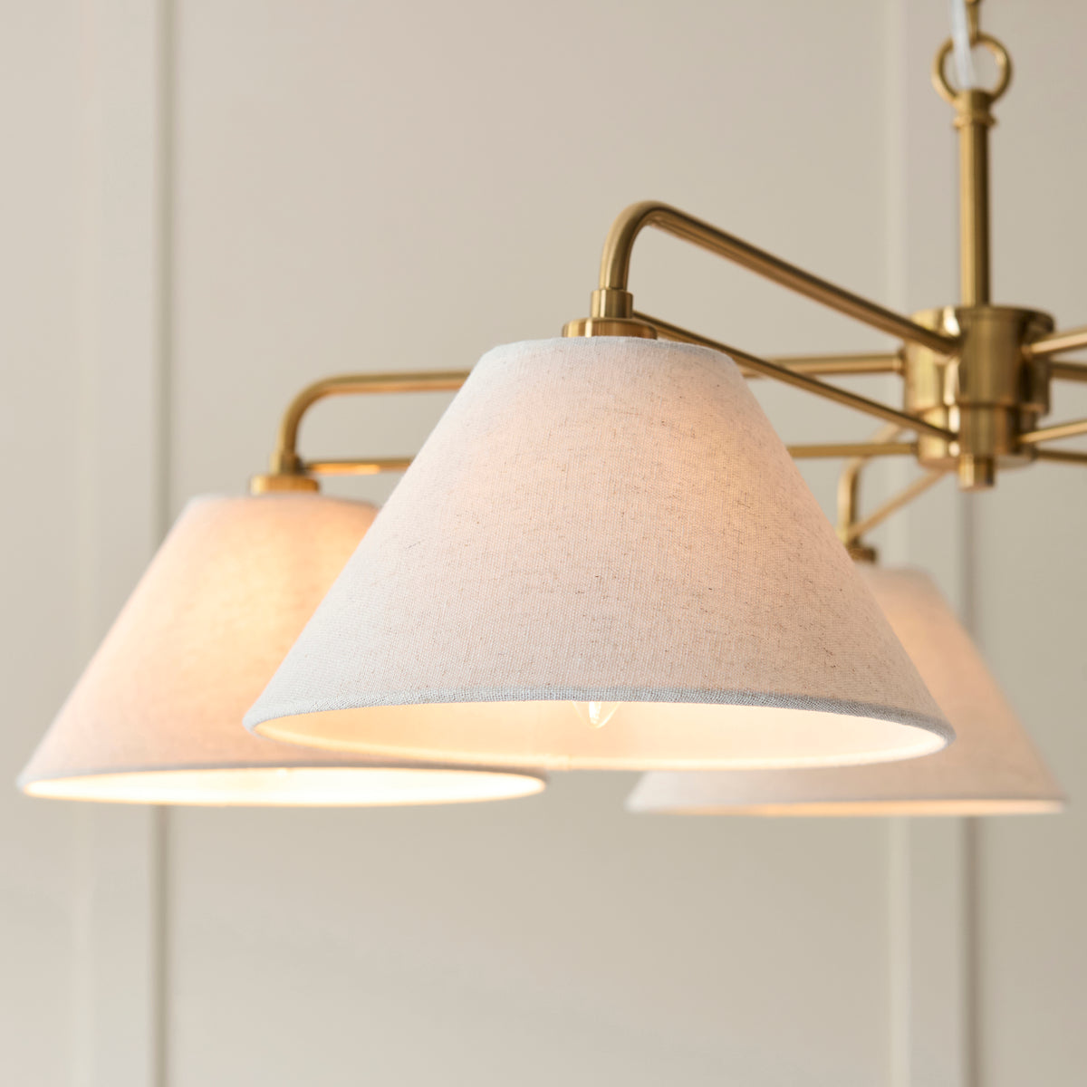 Close-up of the Wallbridge pendant's oatmeal linen coolie shade and brass arm