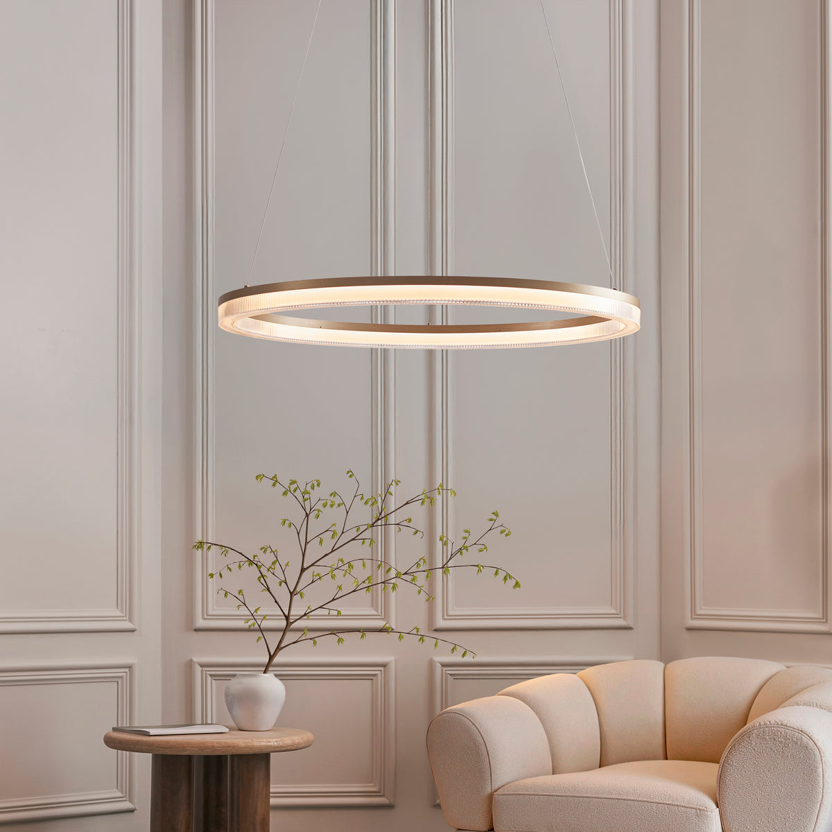 Lansina illuminated gold ring pendant above a side table with blossom branches in a vase