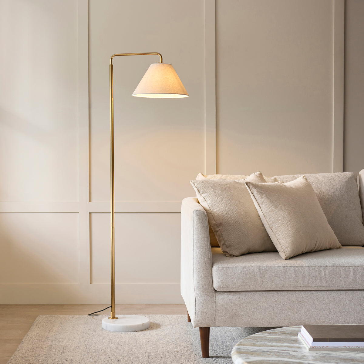 Wallbridge brass floor lamp beside a cream sofa in a panelled living room with wool rug