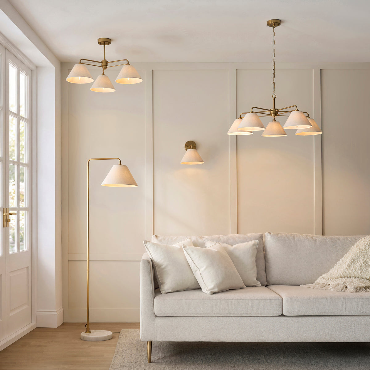 Living room lit by Wallbridge brass floor, wall and ceiling lights above a cream sofa