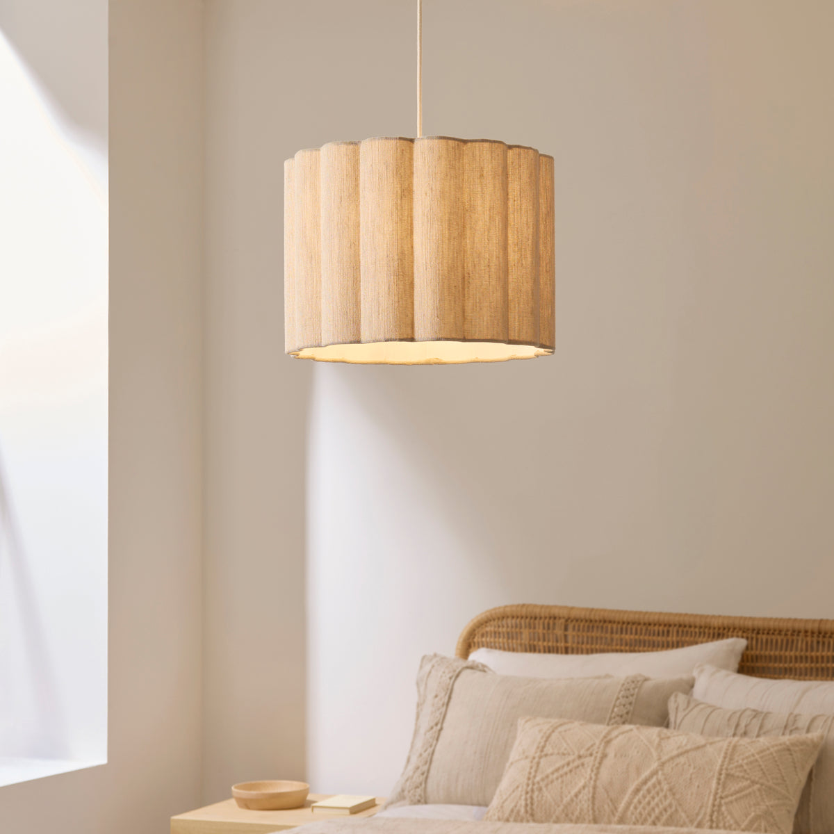 Olson scalloped fabric pendant lighting a bedroom above a rattan bed with knitted cushions