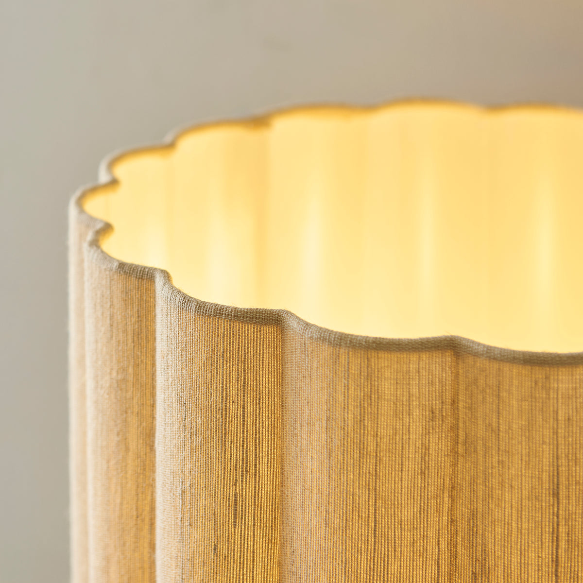 Detail of the Olson lamp's scalloped natural fabric shade with warm light glowing from the cream lining