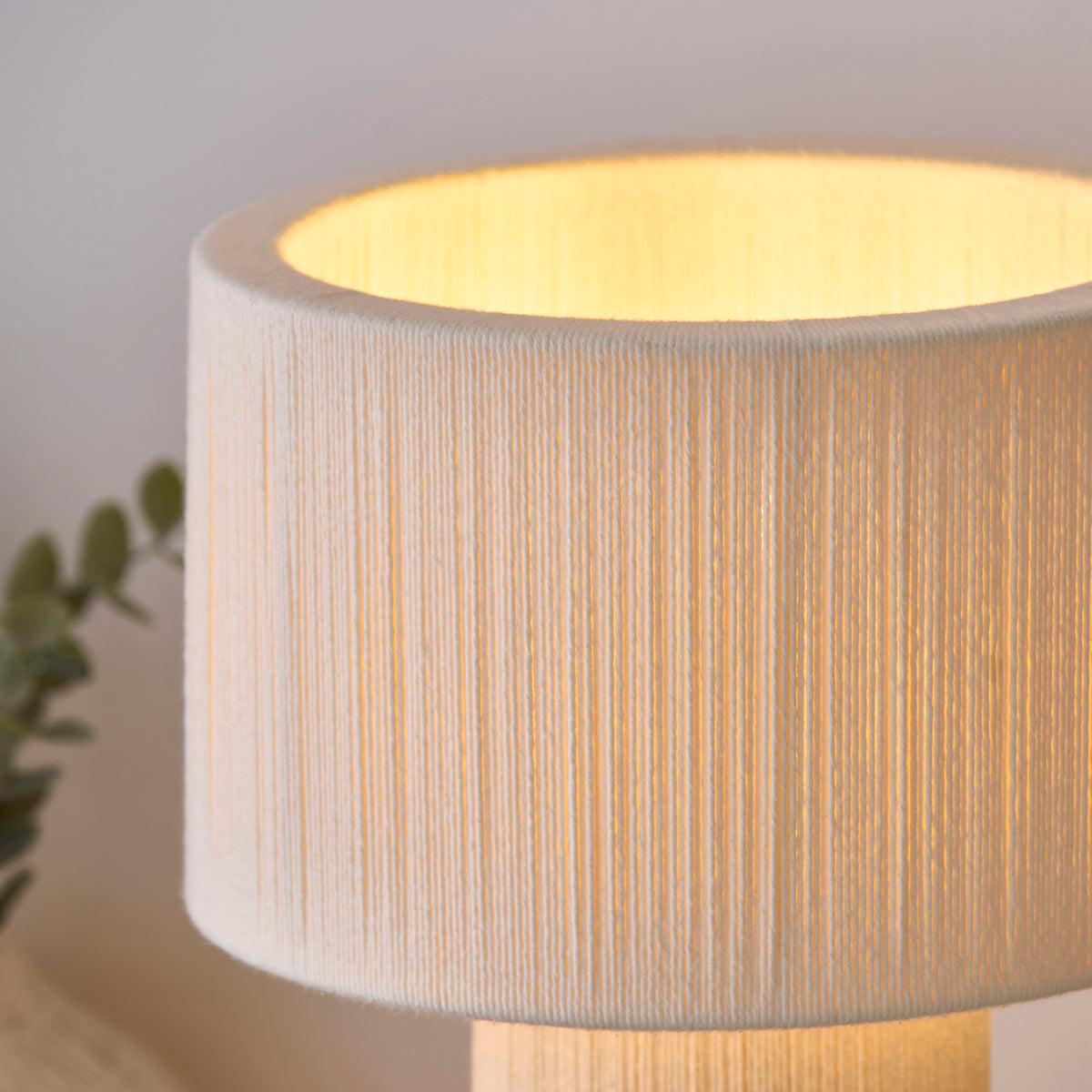 Close-up of the Noah lamp's cream cord-wrapped shade with warm light spilling from inside