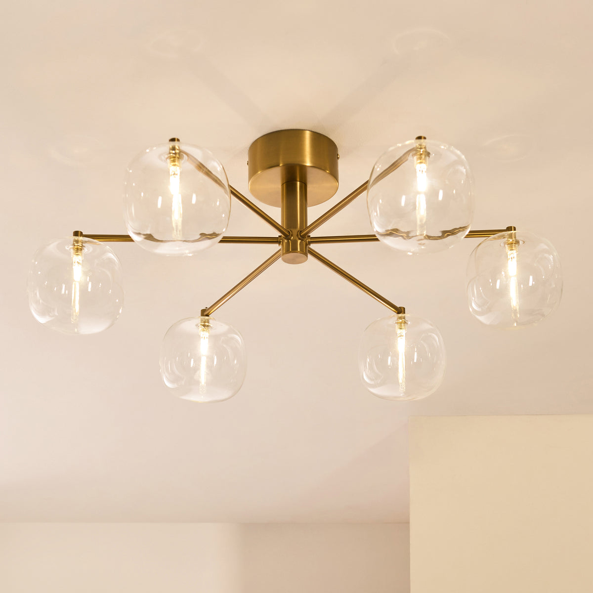 Oslo semi flush light viewed from below showing six clear glass globes and brass spokes