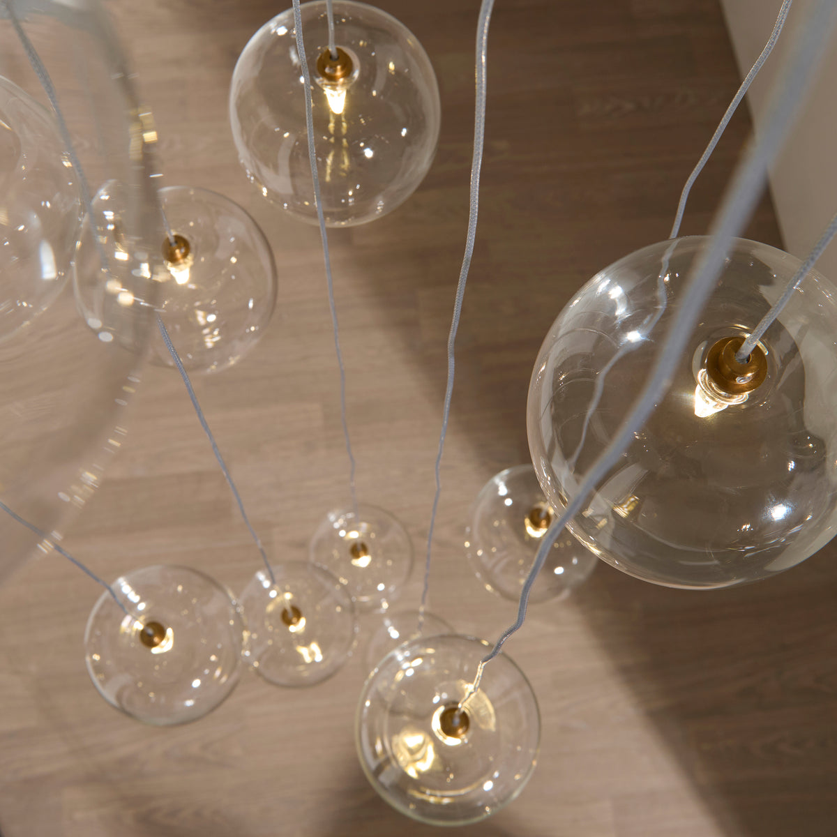 Lit filament bulbs inside the Oslo cascade pendant's clear glass globes viewed from above