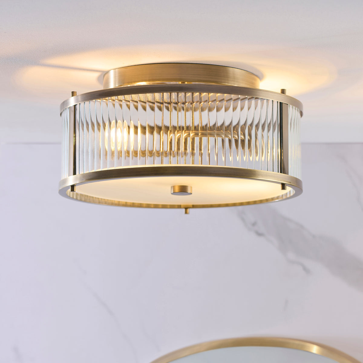 Ridgeton IP44 flush light glowing against a marble bathroom wall and ceiling