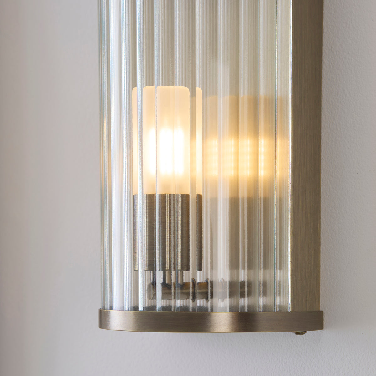 Close-up of the Ridgeton wall light's ribbed glass rods and antique brass base plate