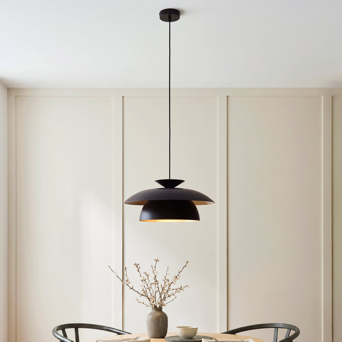 Lyon black pendant hanging over a round oak dining table with blossom vase and wishbone chairs