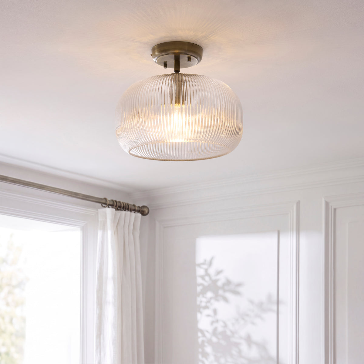 Harborne flush ceiling light glowing in a bright room with curtains and panelled walls