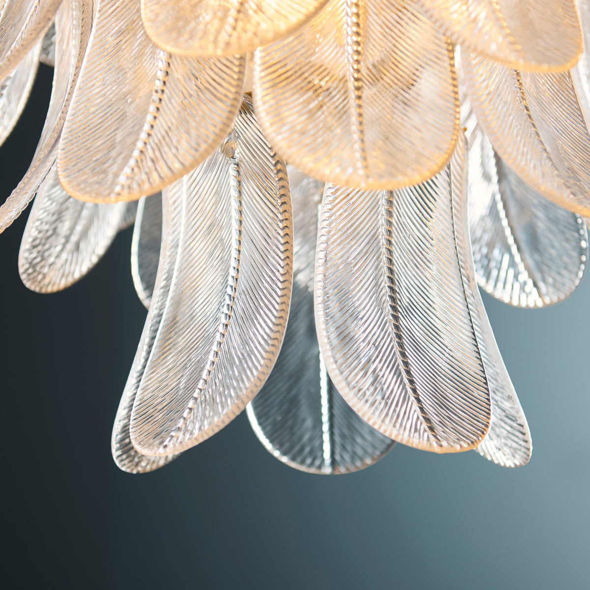 Detail of overlapping textured glass leaves on the lower tier of the Autumn brass chandelier