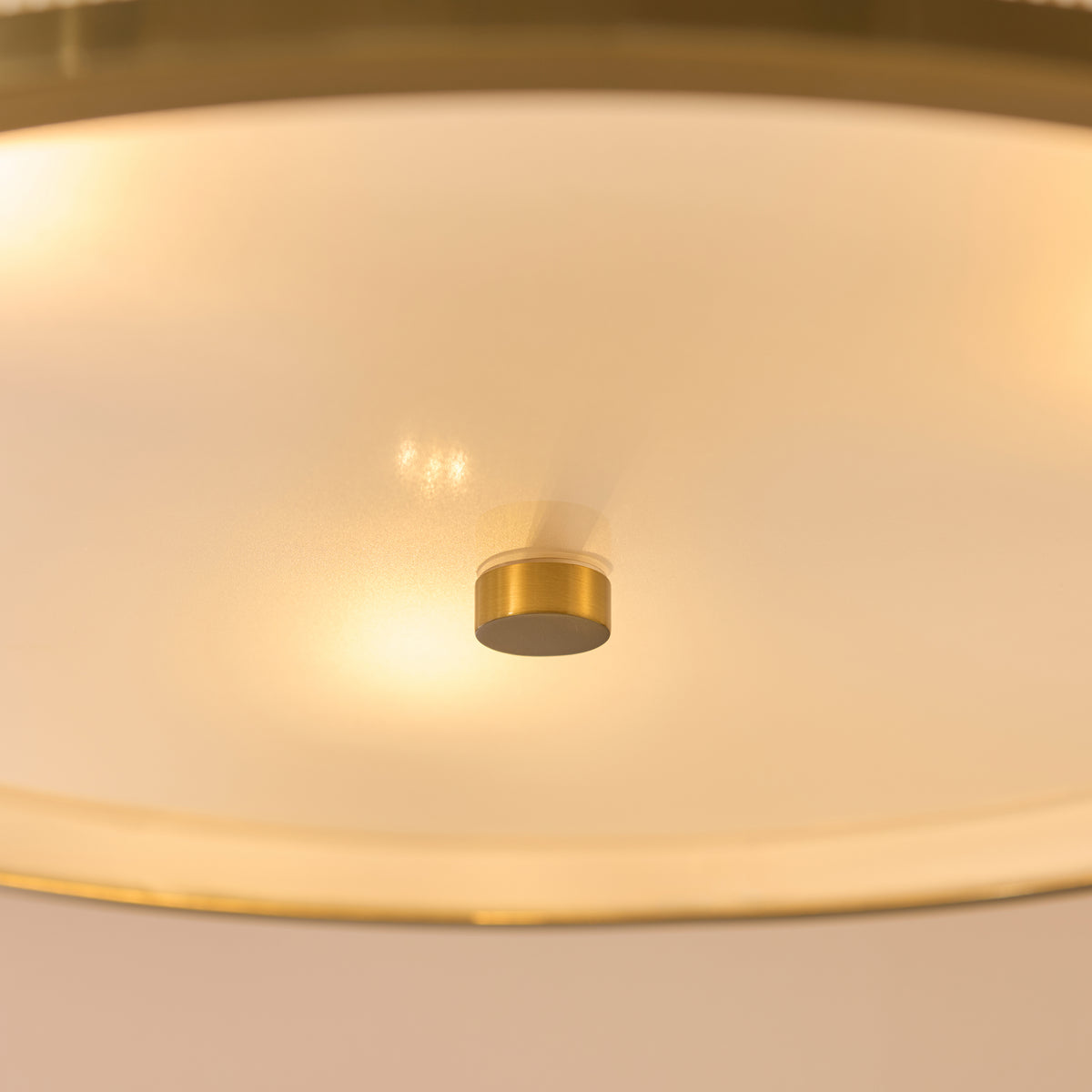 Frosted glass diffuser and small brass finial on the underside of the lit Lexi pendant light