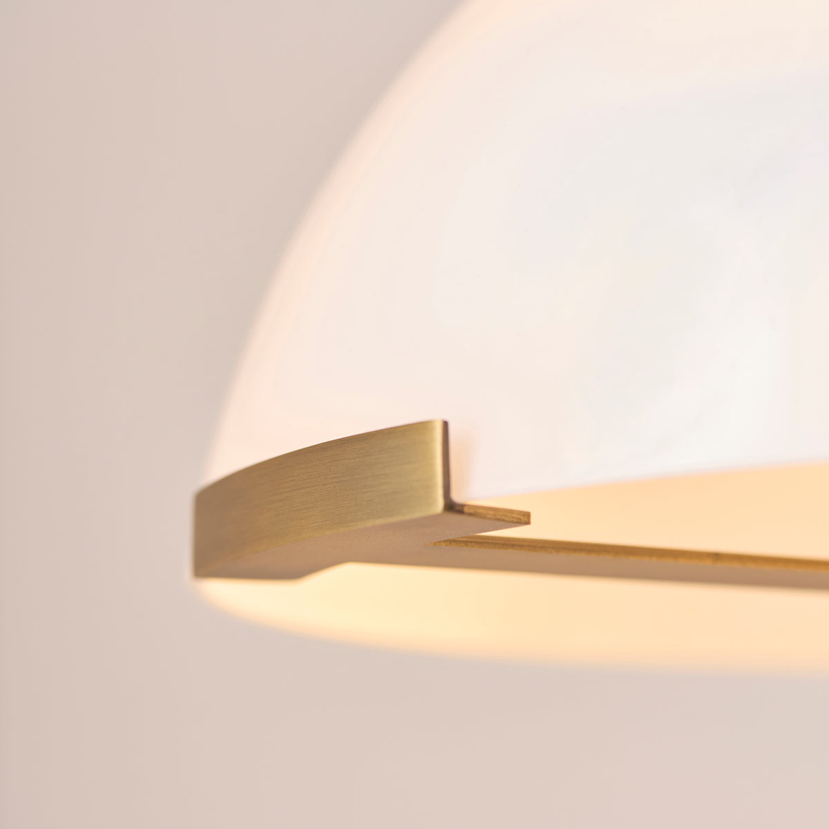 Detail of the Hansel lamp's brass clip holding the rim of the opal glass domed shade