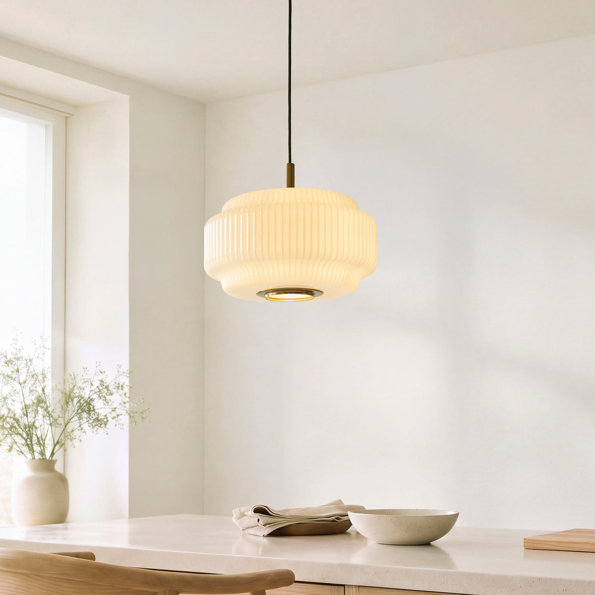 Evora ribbed opal glass pendant lit above a pale kitchen island with bowls and a vase of flowers