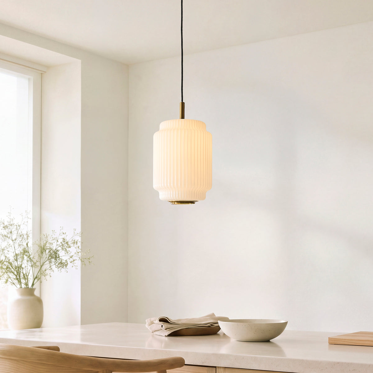 Evora cylindrical ribbed glass pendant lit above a pale kitchen counter beside a window