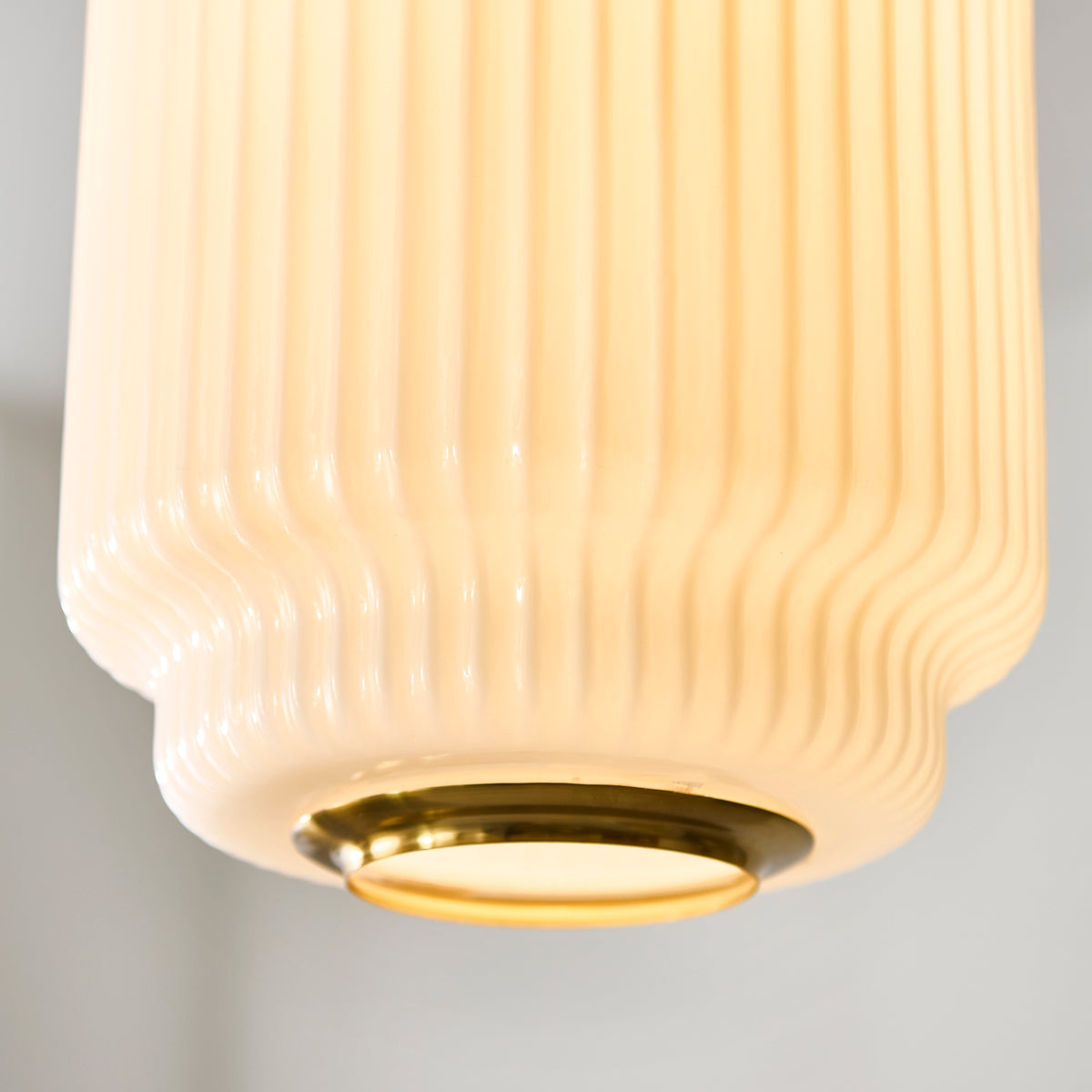 Close-up of the lower ribbed opal glass and polished brass diffuser ring on the Evora pendant