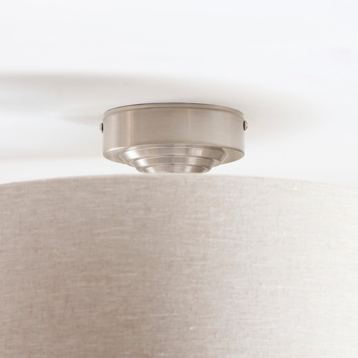 Close-up of the Highclere flush light's brushed chrome ceiling plate against the linen shade